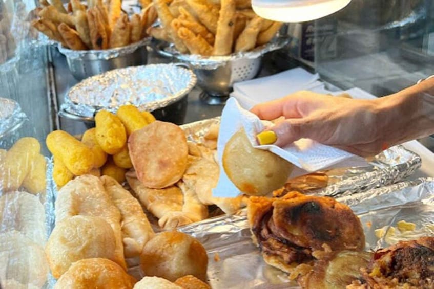 A variety of fried foods, including breadsticks and fried dough balls, displayed in a food stall. 4
