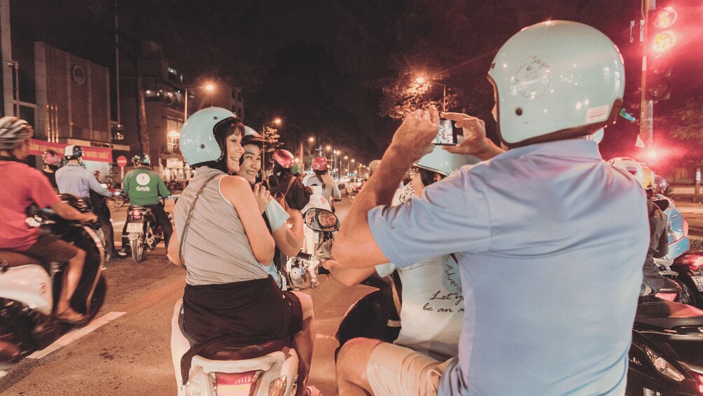 A group of people on scooters on a street at night. 4