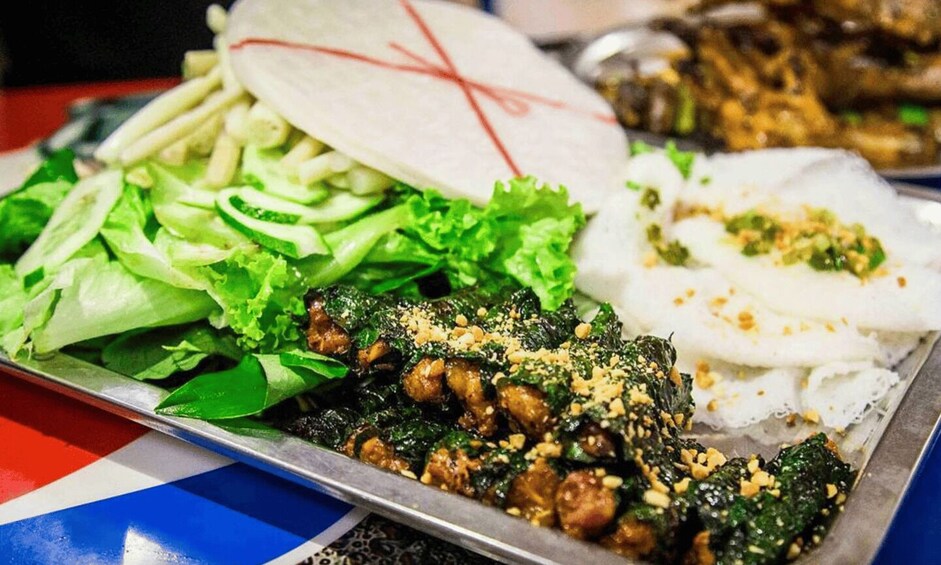 A variety of dishes including stir-fried greens, a noodle dish, and a meat dish on a tray. 3