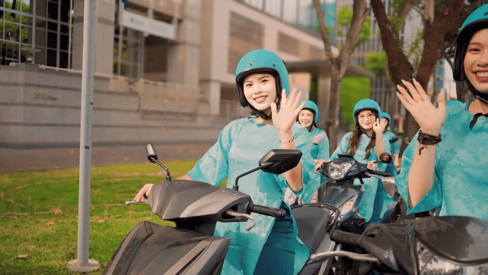 A group of people in teal uniforms and helmets standing next to scooters. 1
