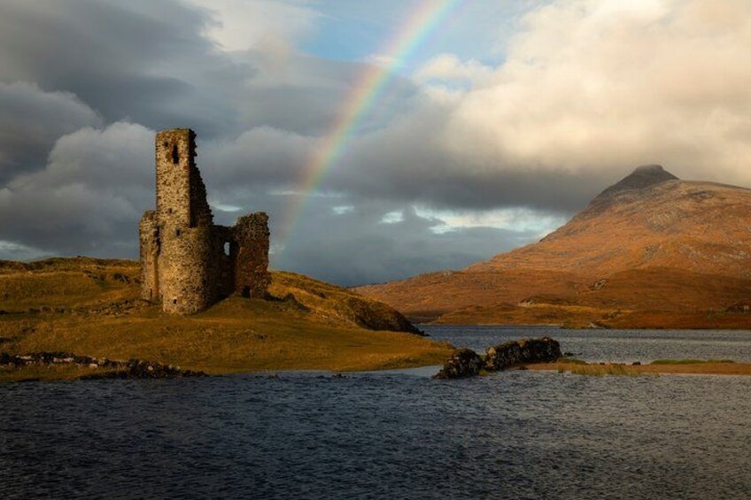A ruined castle, a lake, and a mountain with a rainbow. 1