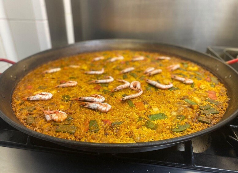 A large pan of paella with shrimp and vegetables. 1