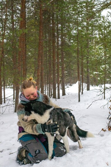 A person hugging a dog in a snowy forest. 1