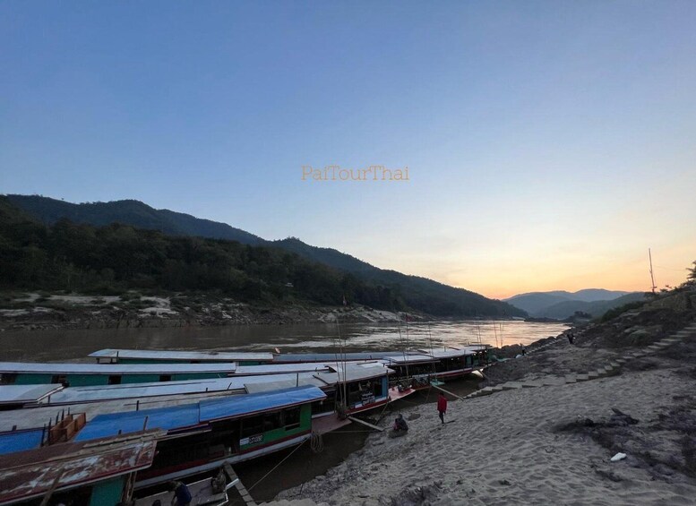 A riverbank with boats docked and a person walking. 3
