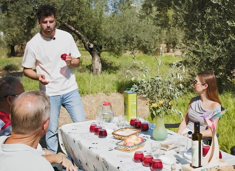 A group of people dining outdoors with a table set for a meal, surrounded by greenery. 1