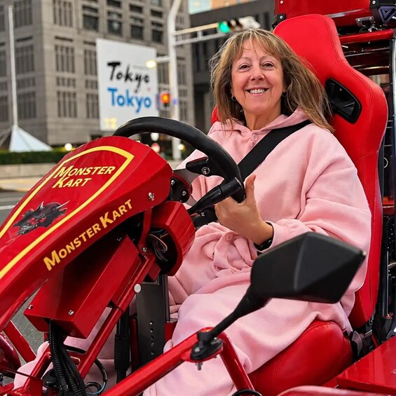 A person in a pink outfit driving a red Monster Kart. 3
