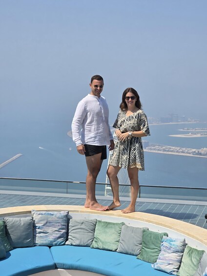 A couple standing on a rooftop with a pool and cityscape view. 4