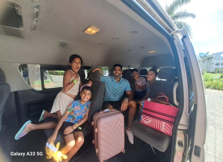 A family inside a Galaxy A33 5G vehicle with a child holding a toy and a pink suitcase. 1