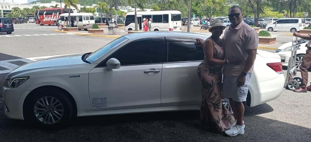 A white car parked on a street with a man and a woman standing beside it. 5