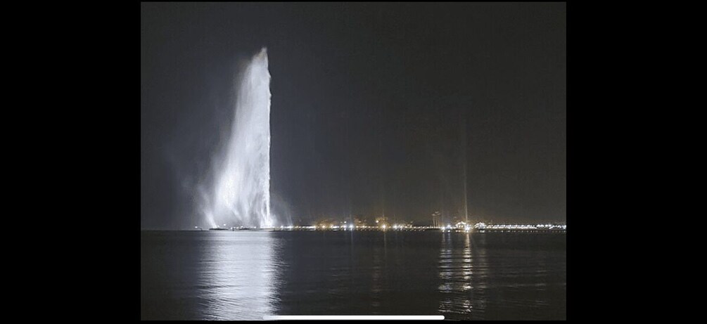 A nighttime fountain with water jets illuminated against a dark sky. 5