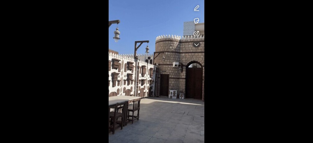 A courtyard with a stone building, a bench, and a lamp post. 4