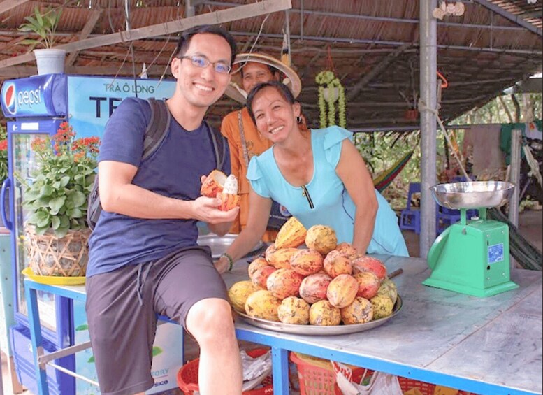 A man and a woman at a food stall with a Pepsi machine, a weighing scale, and a basket of fruits. 4