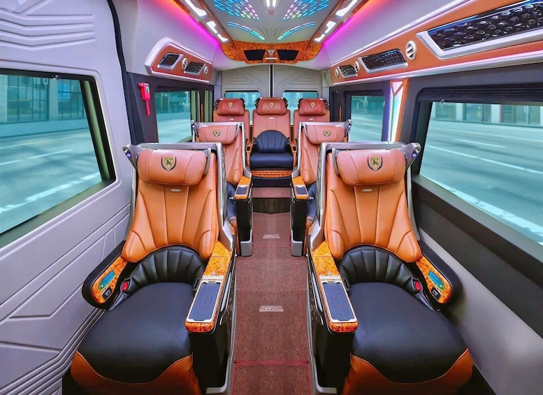 A train interior with leather seats, a central aisle, and overhead lighting. 1