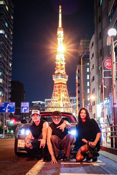 A brightly lit Eiffel Tower at night with three people posing in front of it. 5