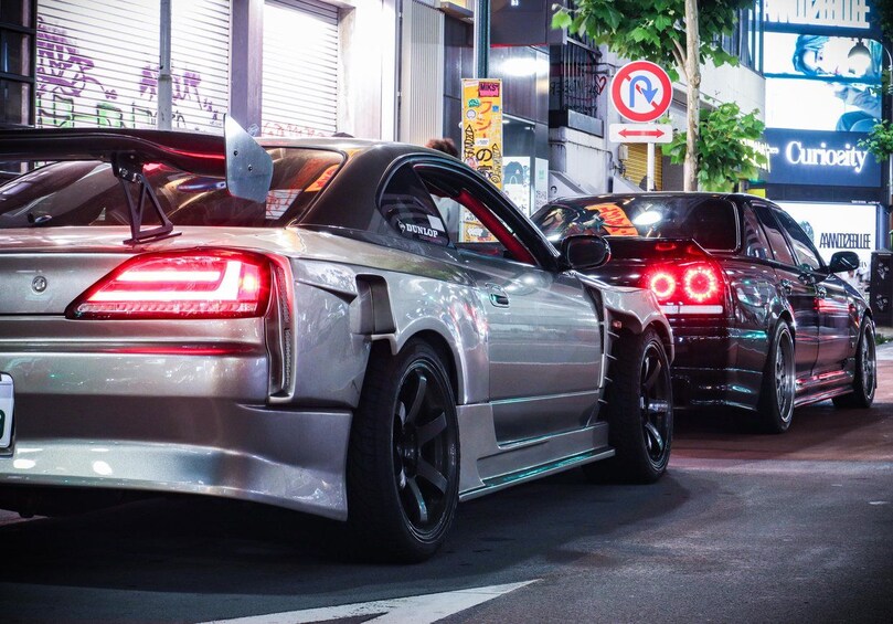 Two cars parked on a city street at night. 1