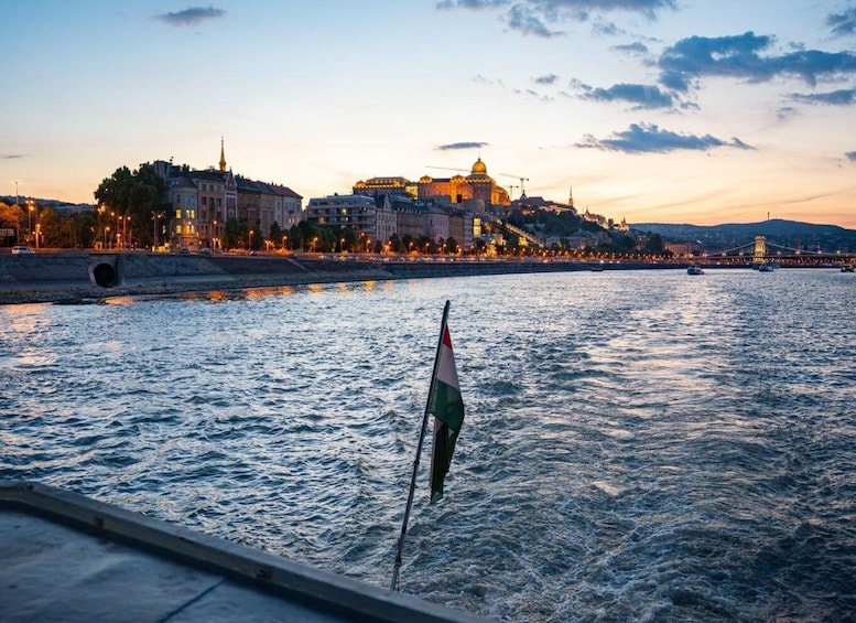 A river with a flag, a cityscape with illuminated buildings, and a bridge in the background. 4