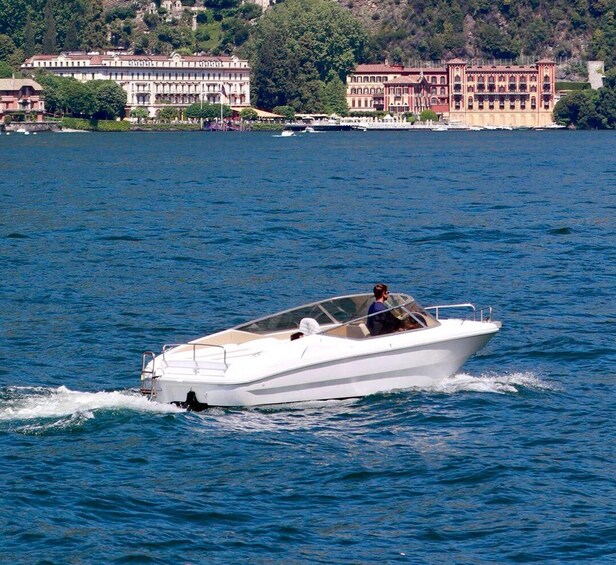 A white motorboat on a calm lake with buildings in the background. 4