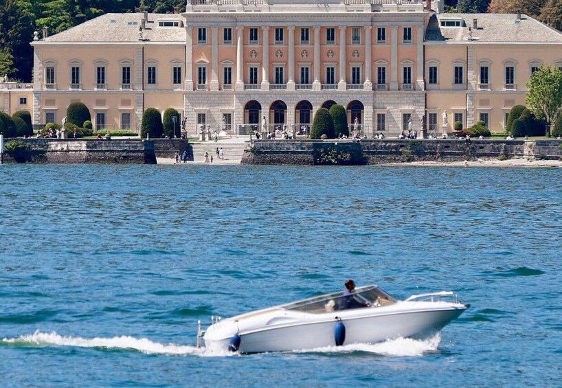 A white motorboat on calm water with a large, classical building in the background. 2