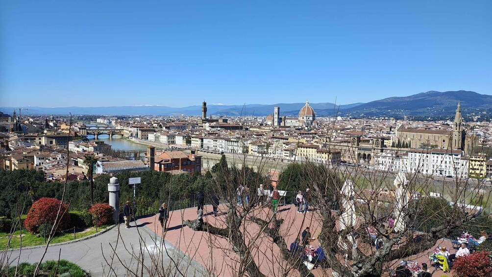 A panoramic view of a city with a prominent river, historic buildings, and a clear blue sky. 1