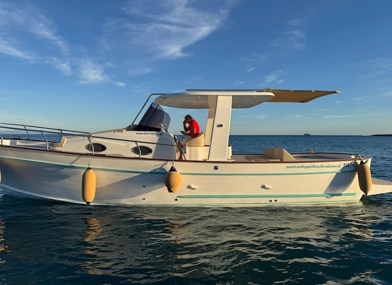 A small motorboat with a canopy, anchored in calm waters. 1