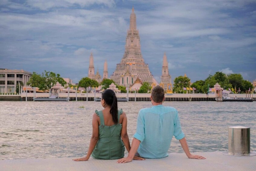 A couple sitting by a river with a large temple in the background. 3