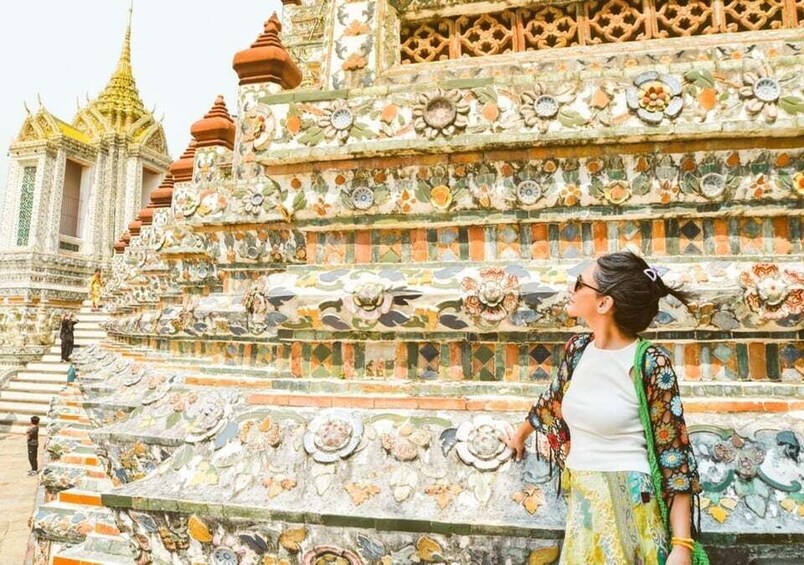 A woman standing in front of a temple with intricate mosaic decorations. 4
