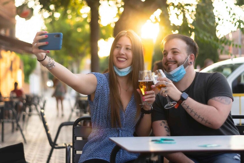 Two people taking a selfie at an outdoor cafe with drinks. 2