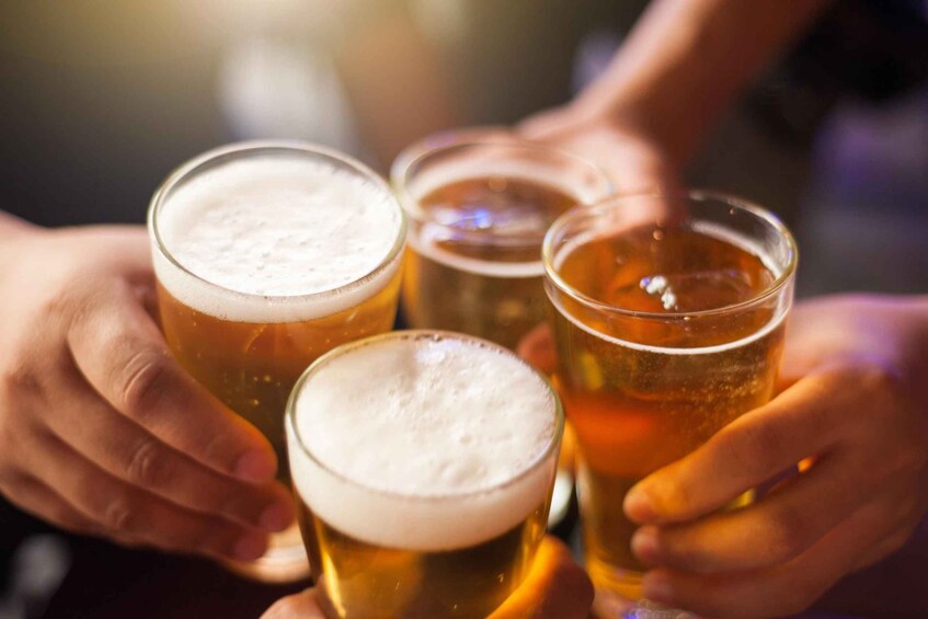 Four glasses of beer being held by people. 3