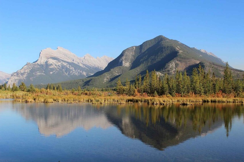 A calm lake reflecting mountains and coniferous trees. 5