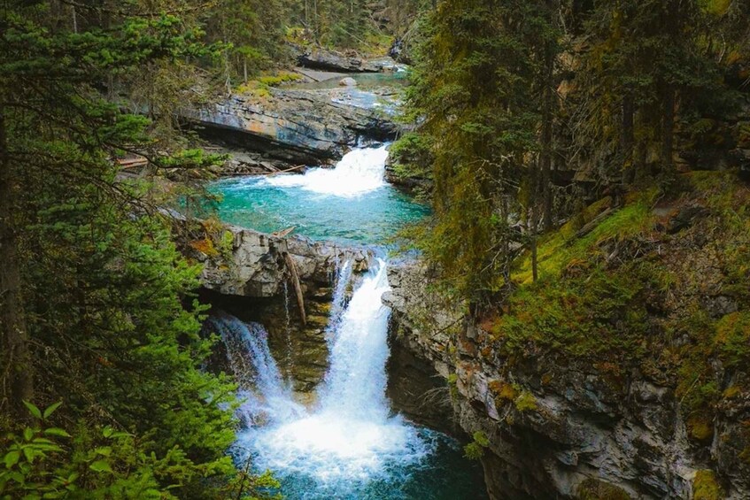 A waterfall cascading through a forested gorge with clear turquoise water. 4