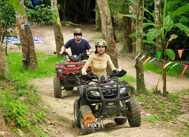 Two people riding ATVs on a dirt path surrounded by trees. 4