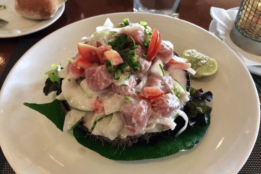 A plate of ceviche with avocado and green onions on a bed of lettuce. 2