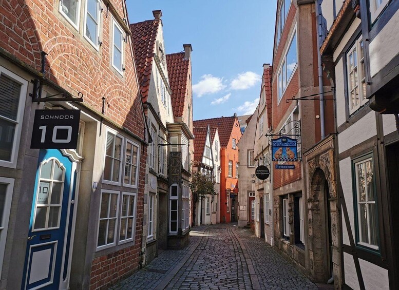 A narrow cobblestone street lined with historic buildings, including a restaurant sign and a number sign '10'. 5