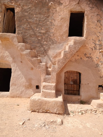 A stone staircase leading to a wooden door in a desert setting. 1