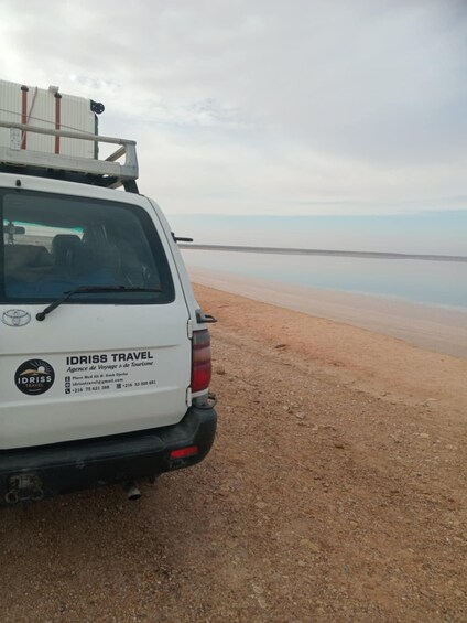 A white SUV parked on a sandy beach with a calm sea in the background. 5