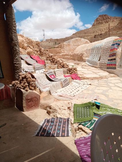 A collection of colorful textiles laid out on stone steps in a desert setting. 3