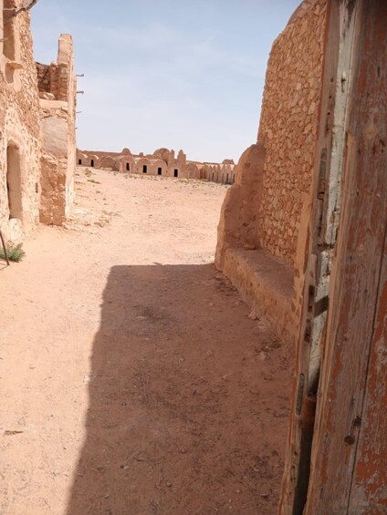 An ancient stone pathway leading through a desert landscape with ruins in the background. 5