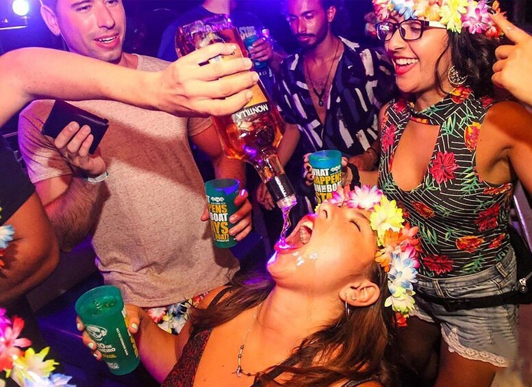 A group of people at a party, holding drinks and wearing festive attire. 1