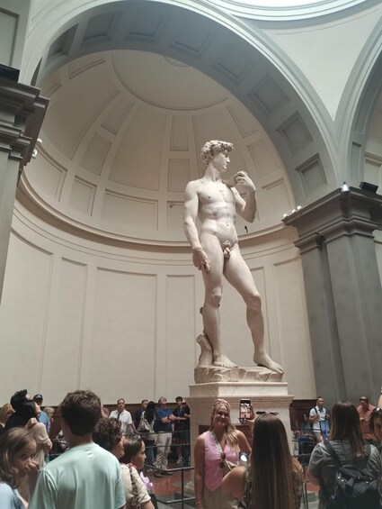 A marble statue of a male figure in classical attire, standing in a grand hall with a high arched ceiling and ornate moldings. 2