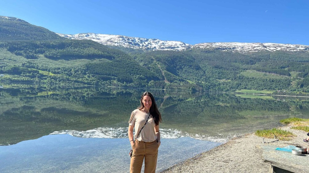 A woman standing by a lake with snow-capped mountains in the background. 3