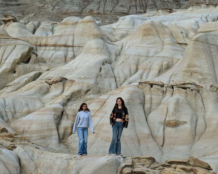 Two individuals standing on a rocky terrain with undulating formations. 5