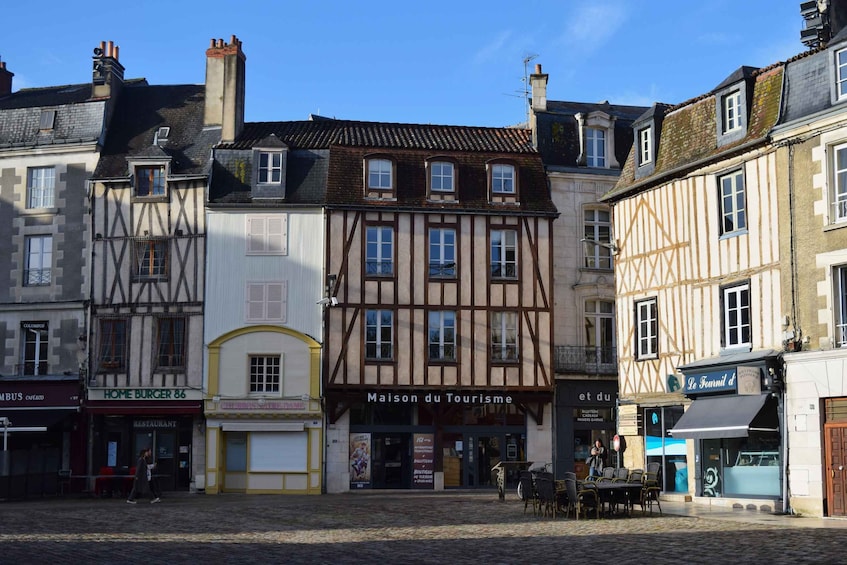 A cobblestone square with historic buildings, a restaurant, and a tourism office. 2