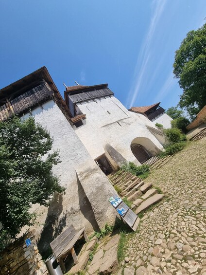 A historic stone building with a steeply pitched roof, a wooden door, and a cobblestone path leading up to it. 4