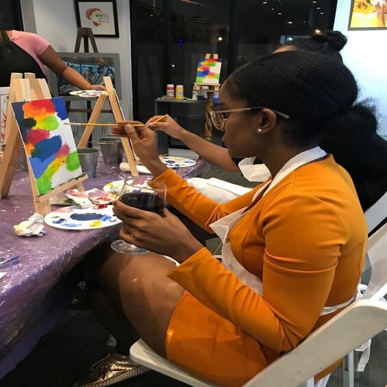 A person painting on an easel with a palette and brushes on a table. 4