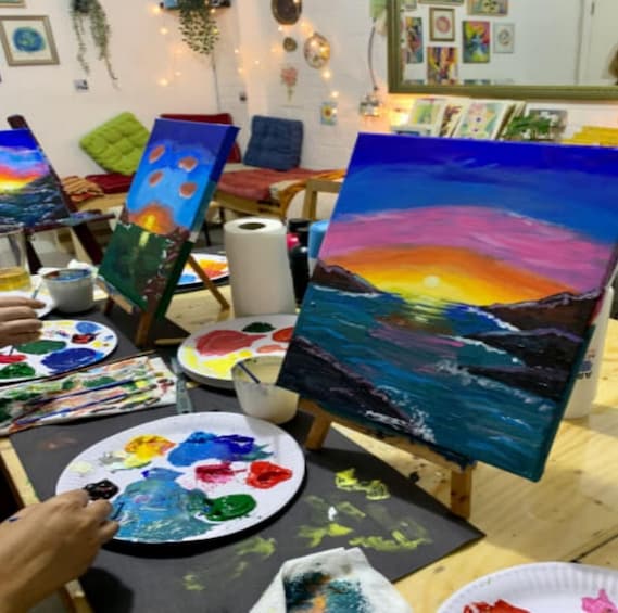 A painting studio with easels, paint palettes, and art supplies. 5