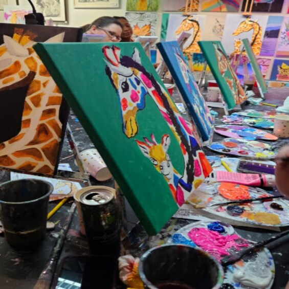 A painting studio with artworks on easels, paint palettes, and art supplies. 2
