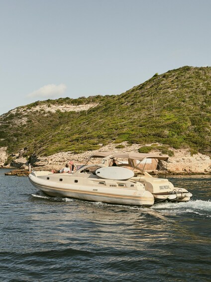 A yacht on calm waters near a rocky coastline with sparse vegetation. 4