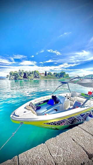 A boat docked at a pier with a clear blue sky and a rocky shoreline in the background. 4