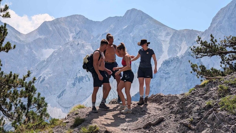A group of hikers on a mountain trail with a backdrop of rugged peaks. 3
