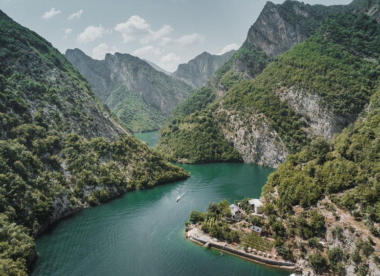A river winding through a mountainous landscape with dense greenery and a small settlement on the right bank. 1